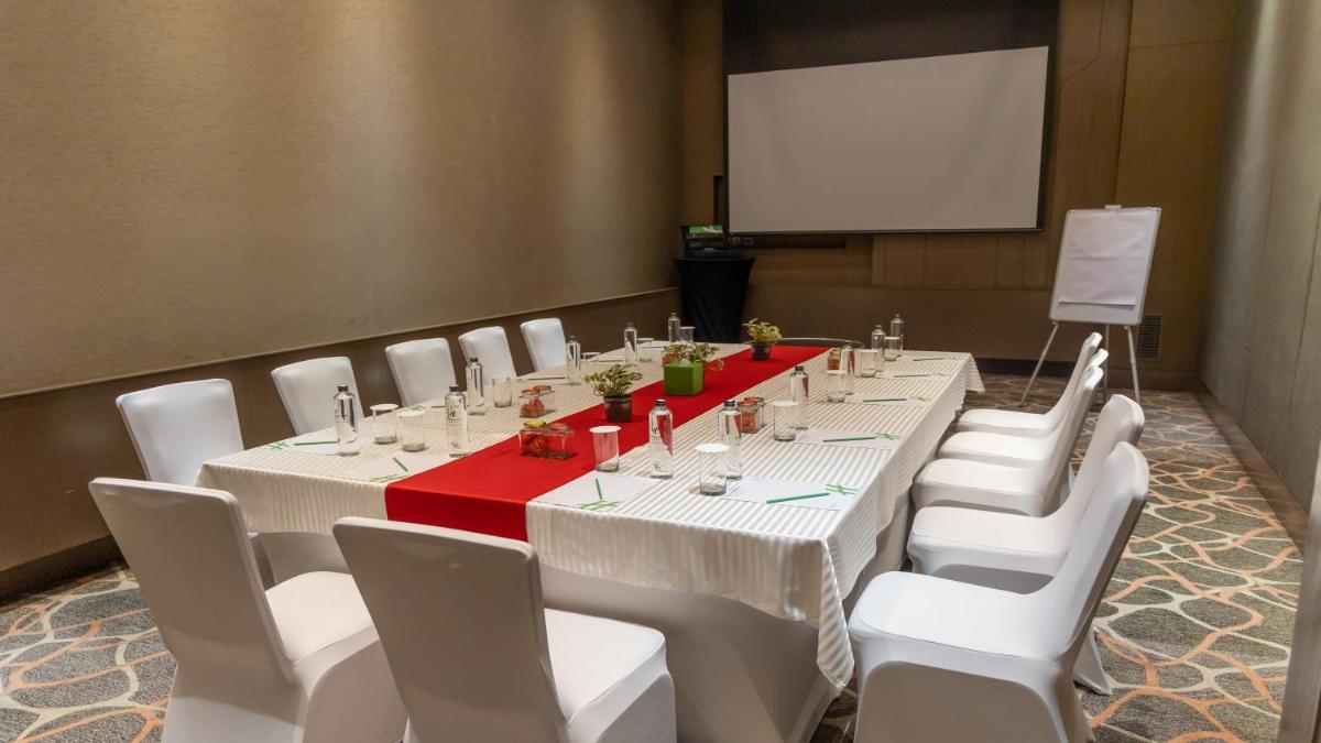 a conference room with a long table with white chairs and a screen at Holiday Inn New Delhi Aerocity by IHG in New Delhi