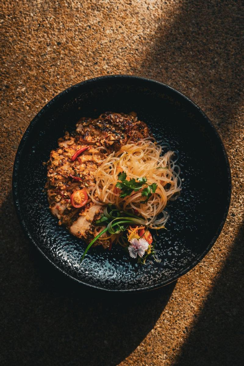 a black bowl of food with noodles and vegetables at Fairmont Jaipur in Jaipur