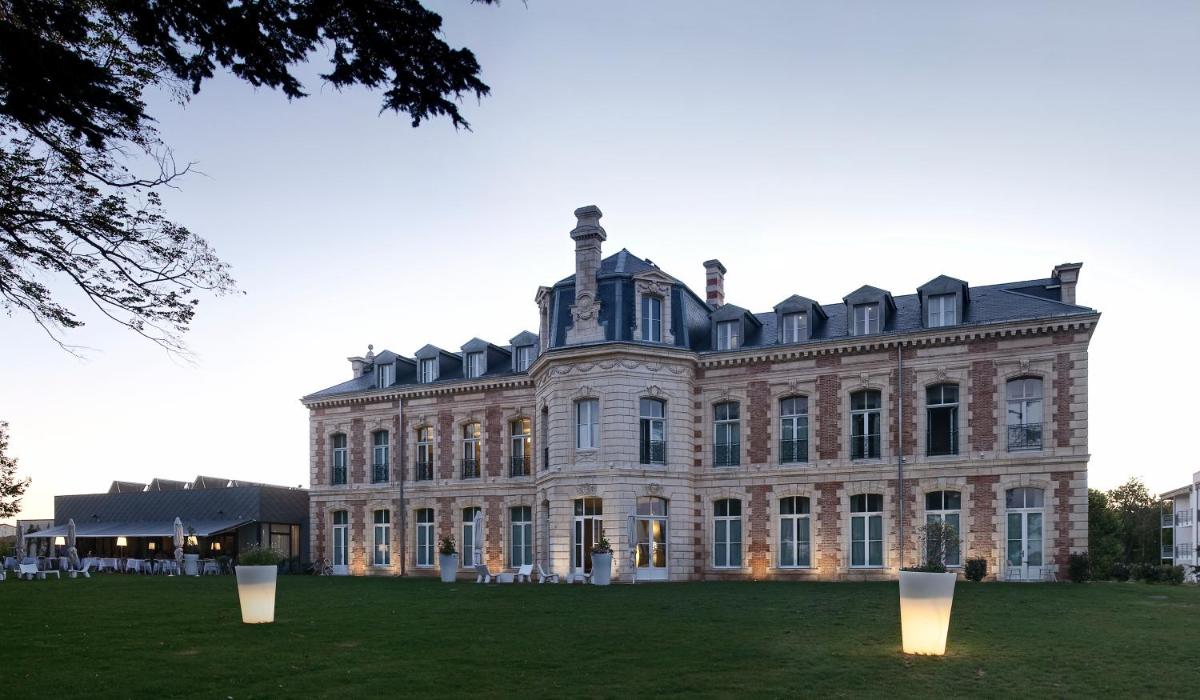 une grande maison avec des lumières devant dans l'établissement Hôtel et SPA du Château, à Lagord