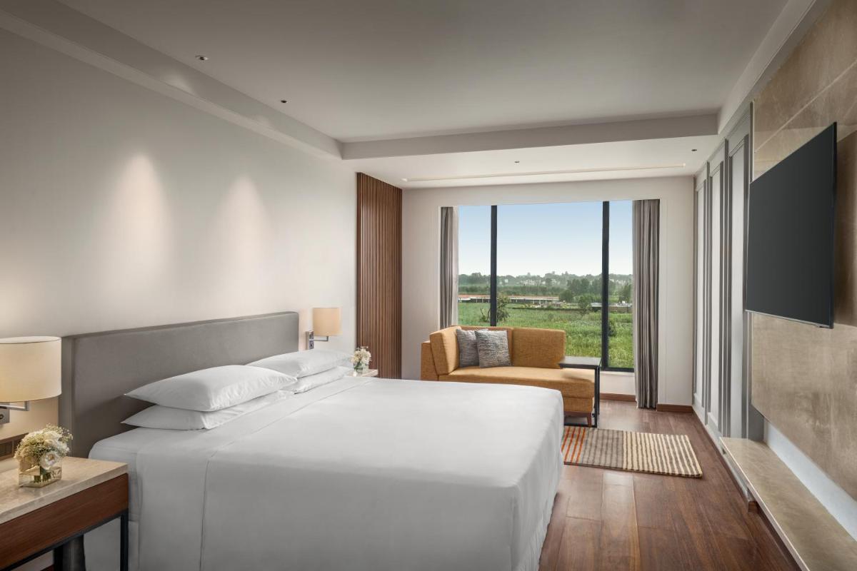 a bedroom with a large white bed and a chair at Hyatt Place Haridwar in Haridwār