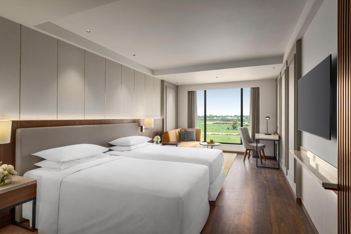 a bedroom with a large white bed and a desk at Hyatt Place Haridwar in Haridwār