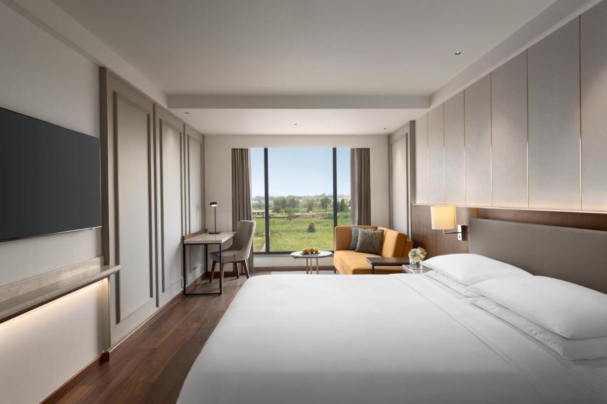 a hotel room with a large bed and a television at Hyatt Place Haridwar in Haridwār