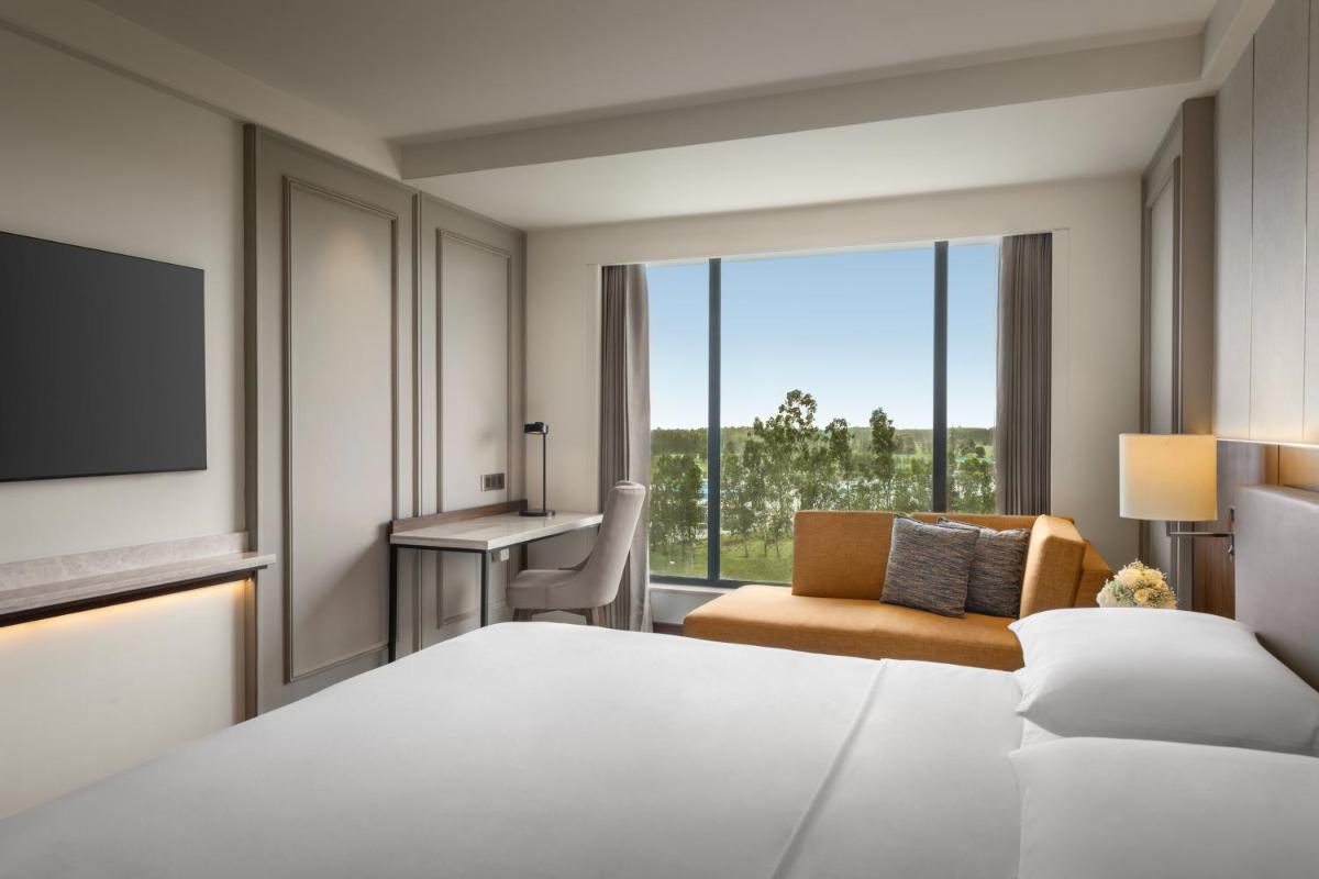 a hotel room with a bed and a desk and a tv at Hyatt Place Haridwar in Haridwār