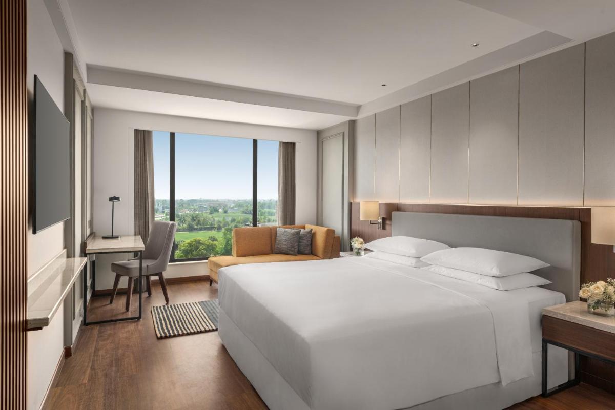 a bedroom with a large white bed and a desk at Hyatt Place Haridwar in Haridwār