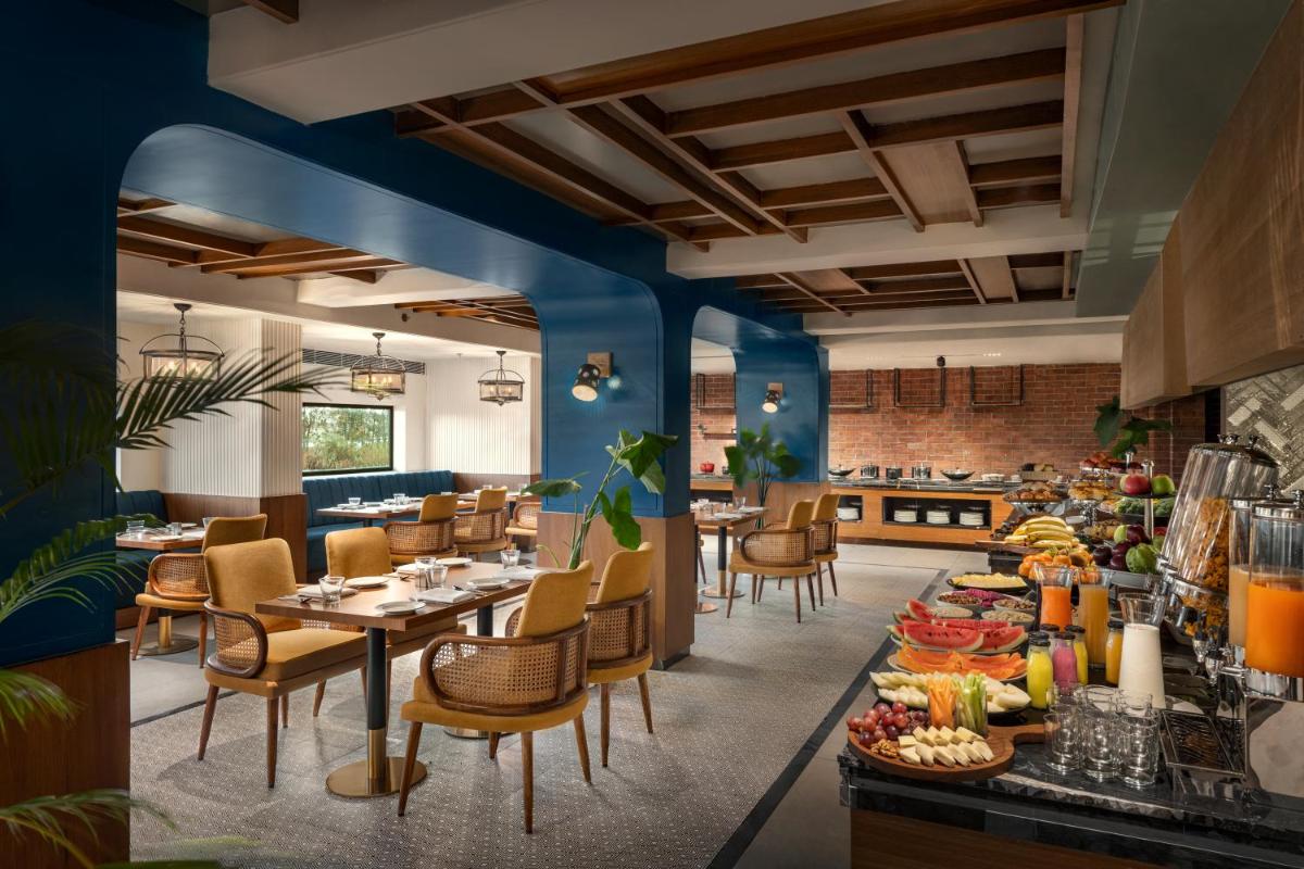a restaurant with blue walls and tables and chairs at Hyatt Place Haridwar in Haridwār