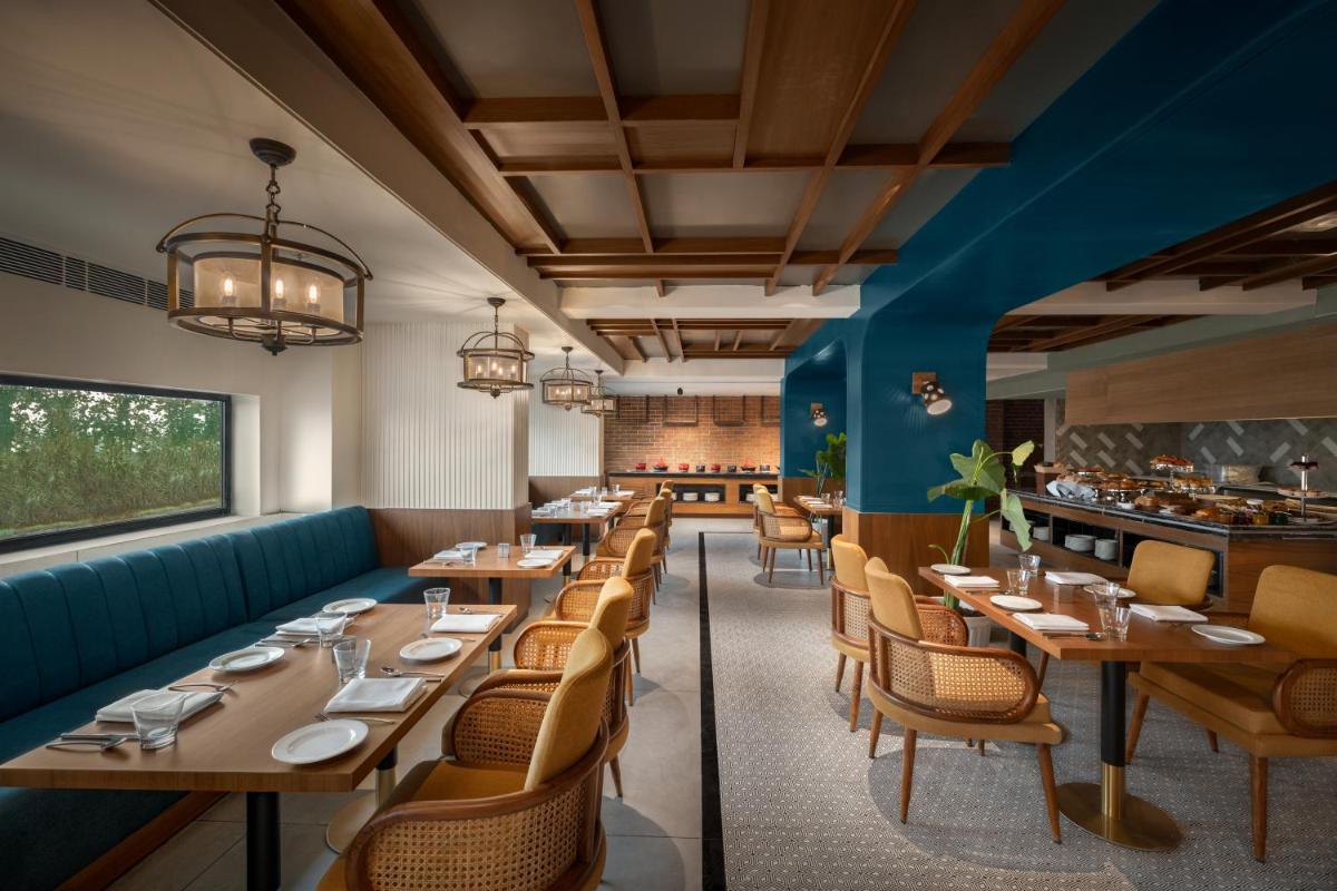 a dining room with wooden tables and chairs at Hyatt Place Haridwar in Haridwār