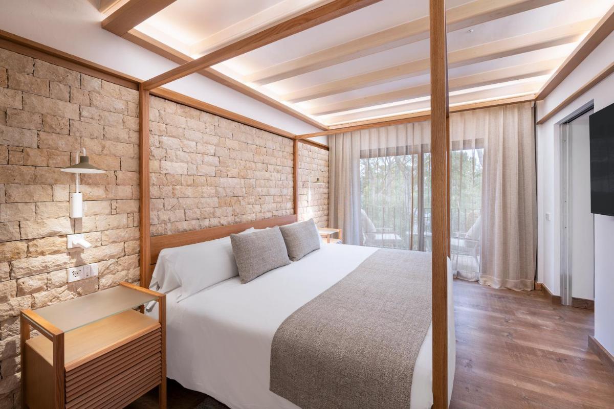 Un dormitorio con una cama blanca y una pared de ladrillo. en Hotel Cala del Pi - Adults Only, en Platja d'Aro 92 fotos más
