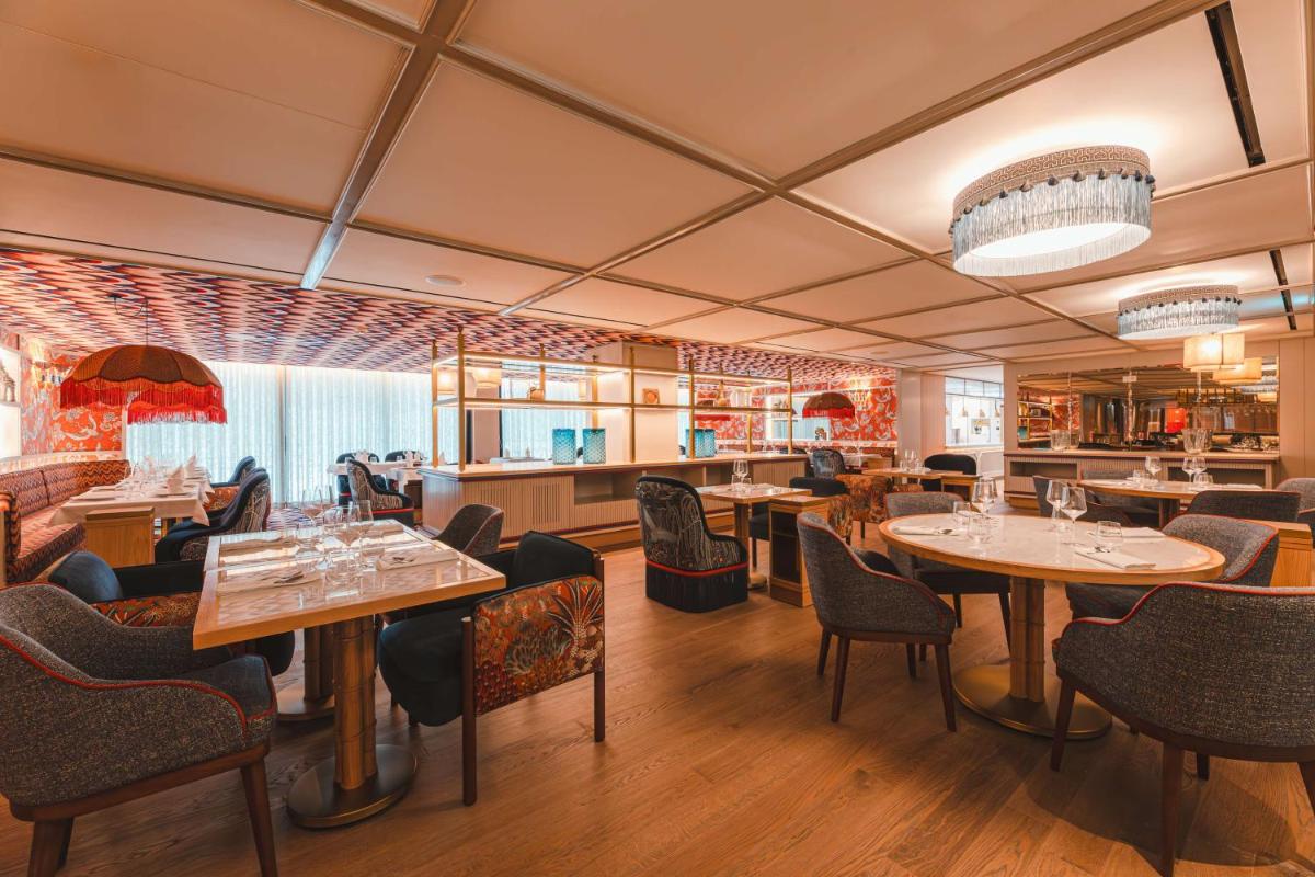 um restaurante com mesas e cadeiras em uma sala em Legacy Hotel Cascais, Curio Collection By Hilton em Cascais