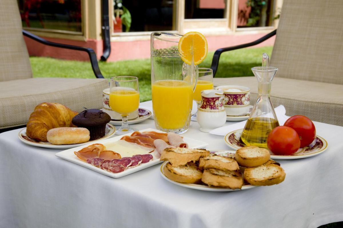 una mesa con platos de comida y vasos de jugo de naranja en Hotel Del Lago, en Puigcerdà