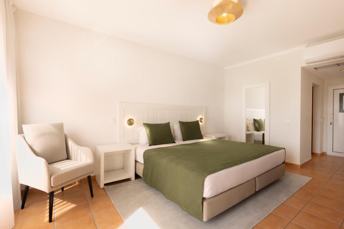 um quarto branco com uma cama e uma cadeira em Hotel Rural Quinta do Marco - Nature & Dining em Tavira mais 37 fotografias