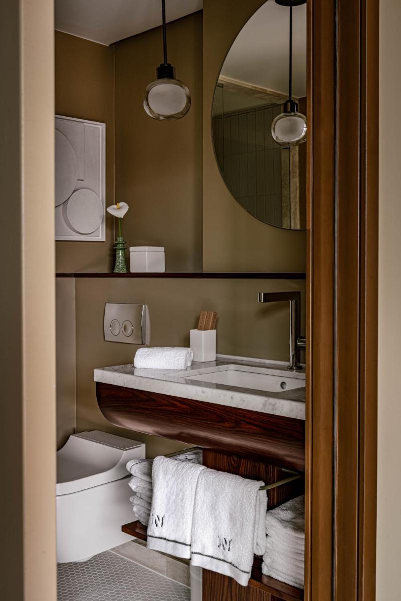 une salle de bains avec lavabo, toilettes et miroir dans l'établissement Norman Paris Hôtel & Spa, à Paris