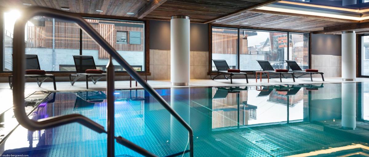 une piscine avec chaises et tables dans un bâtiment dans l'établissement MGM Hôtels & Résidences - Résidence Le Cristal de Jade, à Chamonix-Mont-Blanc