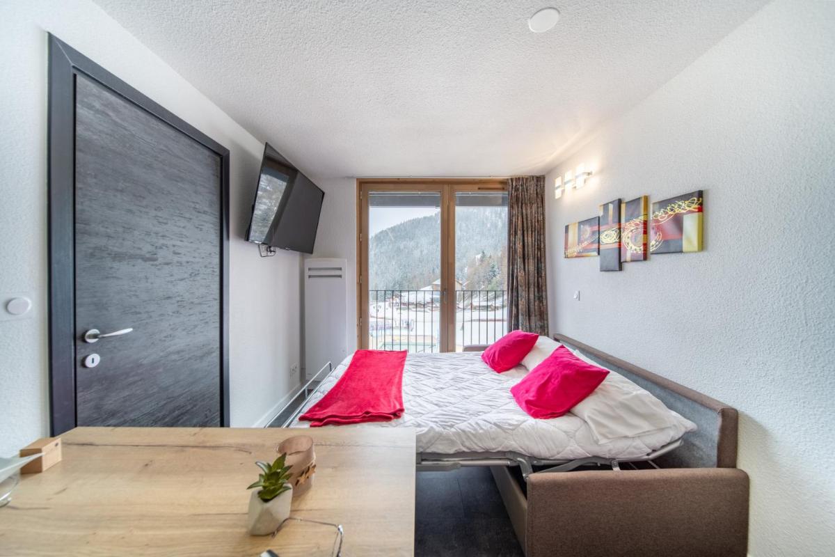 une chambre avec un lit avec des oreillers roses dessus dans l'établissement Résidence Kocoon Les Karellis - Pass activités inclus et accès gratuit et illimité à l'espace aquatique Aquarellis, à Montricher-Albanne