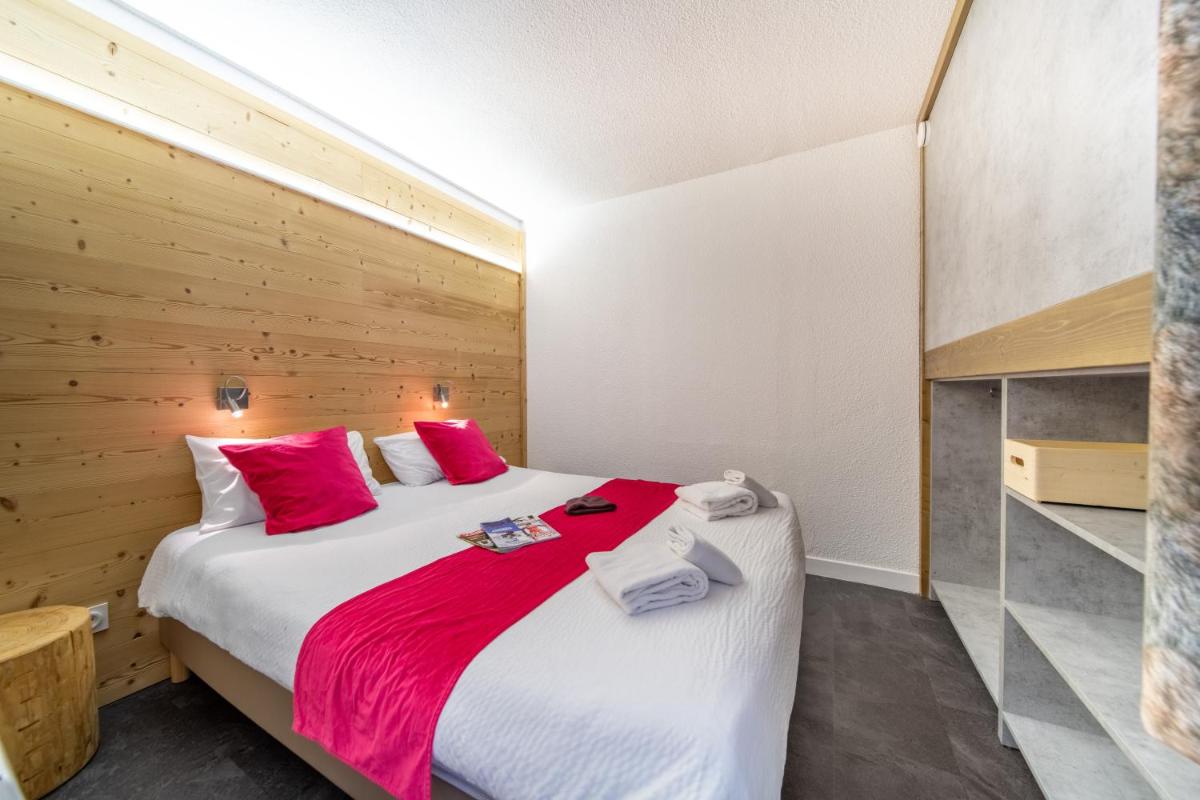 une chambre avec un grand lit avec des oreillers rouges dans l'établissement Résidence Kocoon Les Karellis - Pass activités inclus et accès gratuit et illimité à l'espace aquatique Aquarellis, à Montricher-Albanne