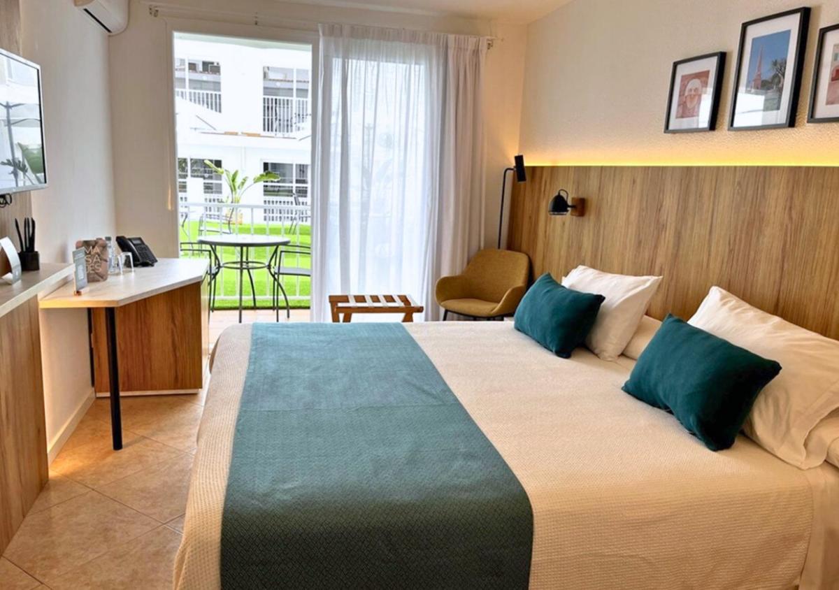 Habitación de hotel con cama grande con almohadas verdes en Alfons Hotel, en Ciutadella 60 fotos más