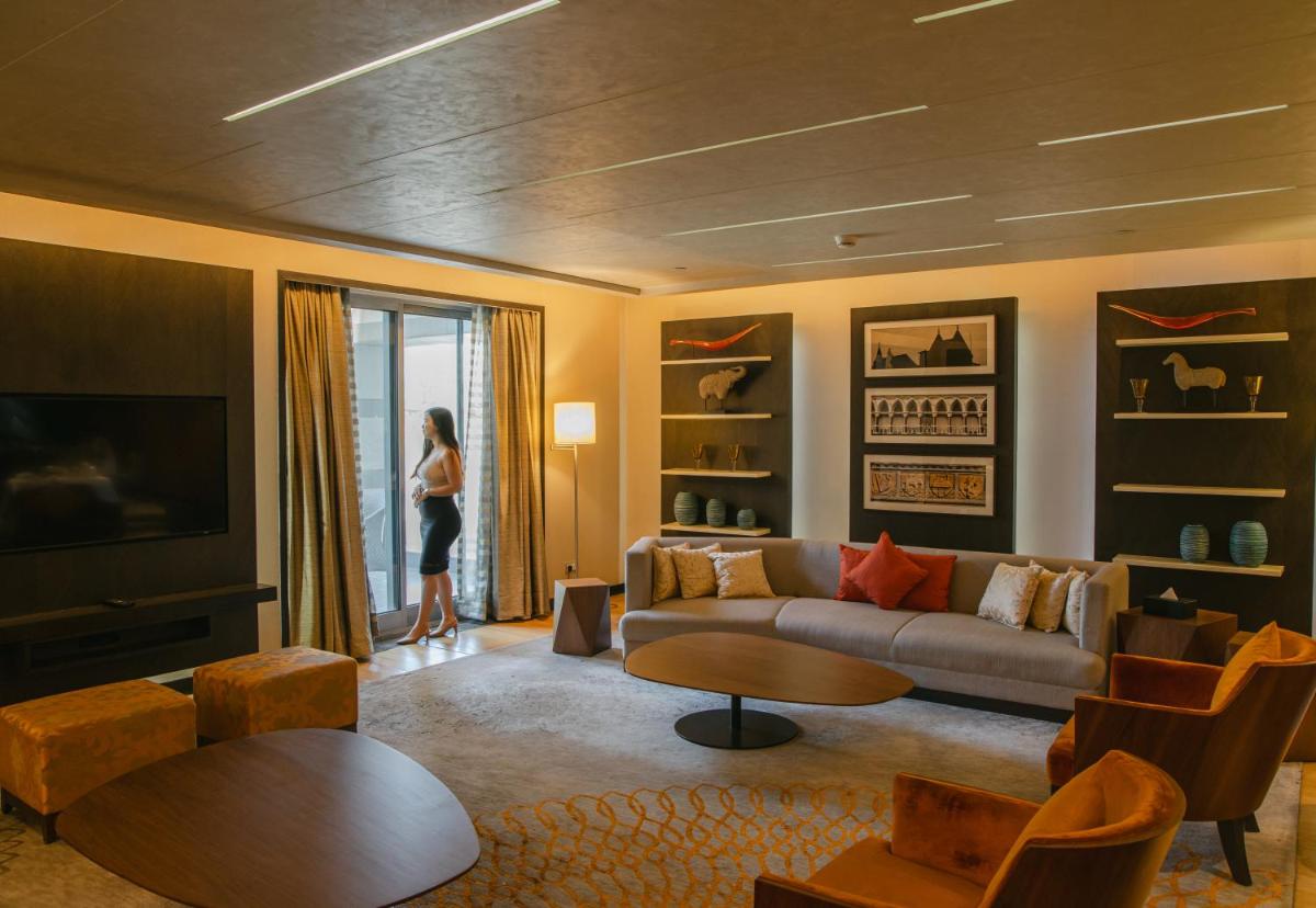 a woman standing in a living room with a couch at Grand Hyatt Mumbai Hotel and Residences in Mumbai