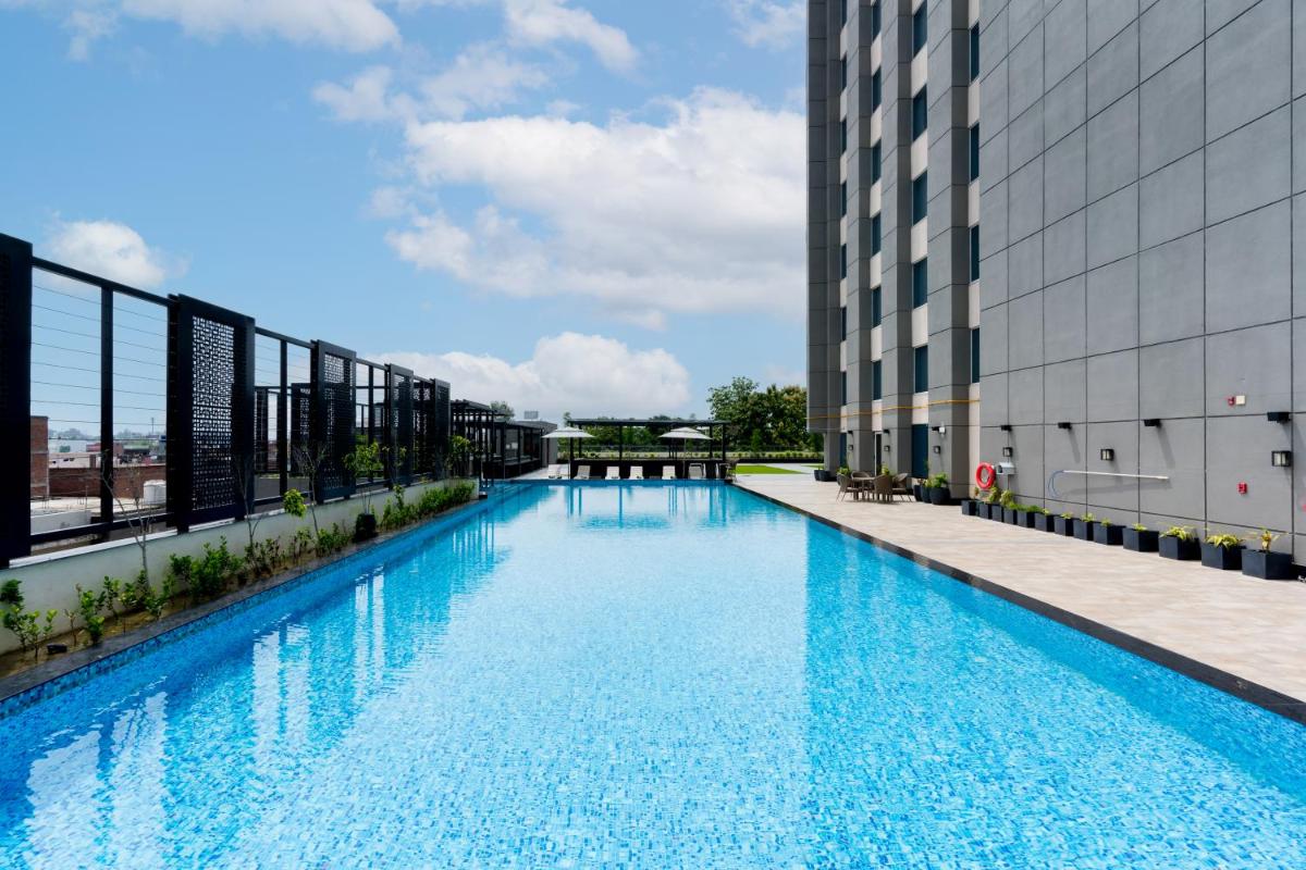 a large swimming pool on the side of a building at Holiday Inn Lucknow Airport by IHG in Lucknow