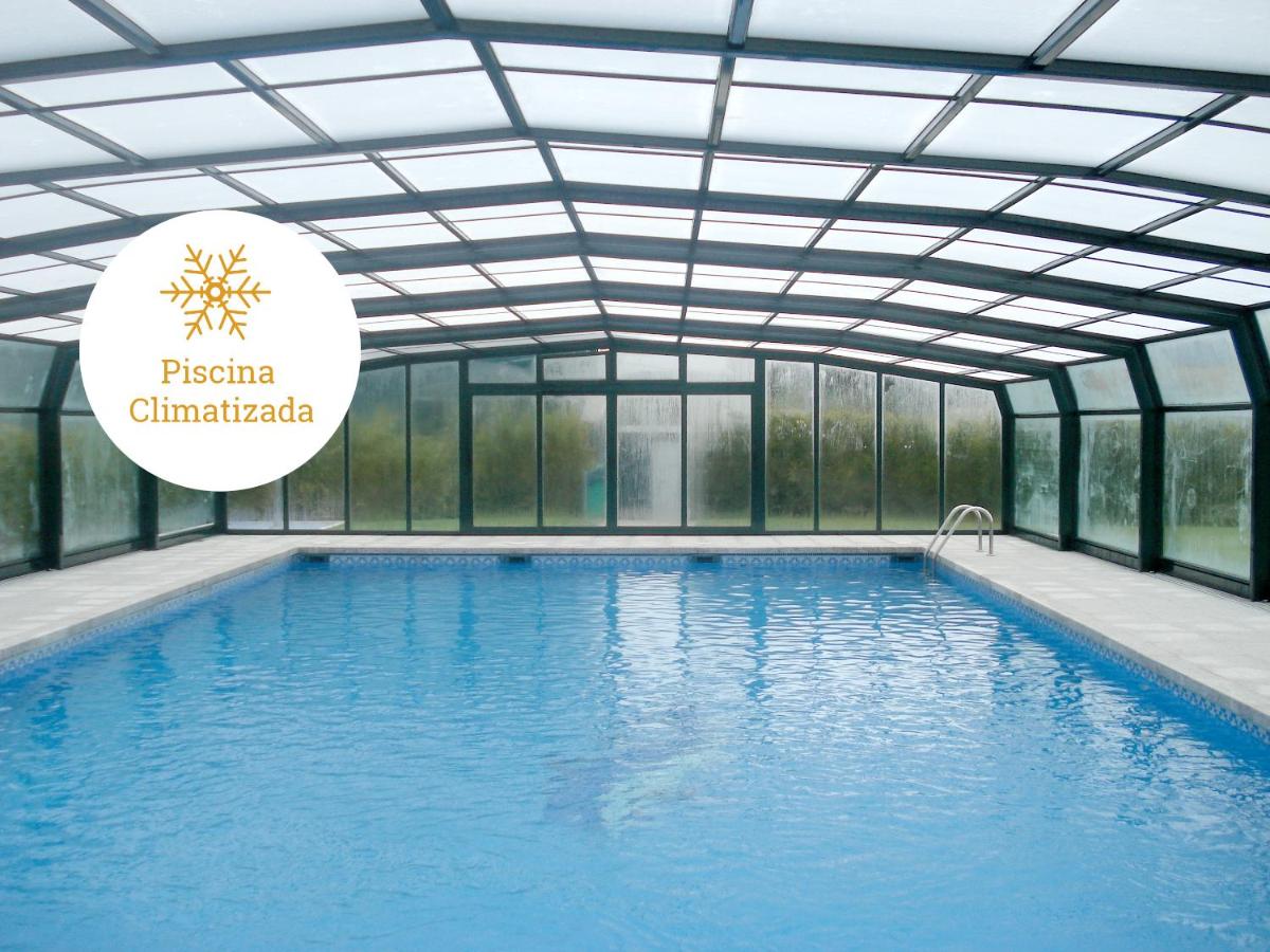 una piscina con techo de cristal con el logotipo de piscina chaminaria en Hotel Auditorio Santiago & Spa, en Lugo