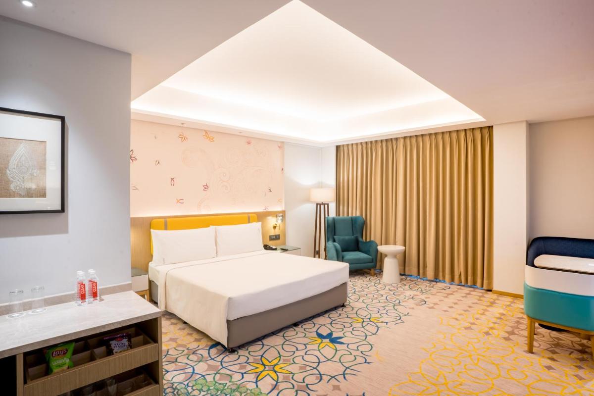 a hotel room with a bed and a chair at Holiday Inn Lucknow Airport by IHG in Lucknow