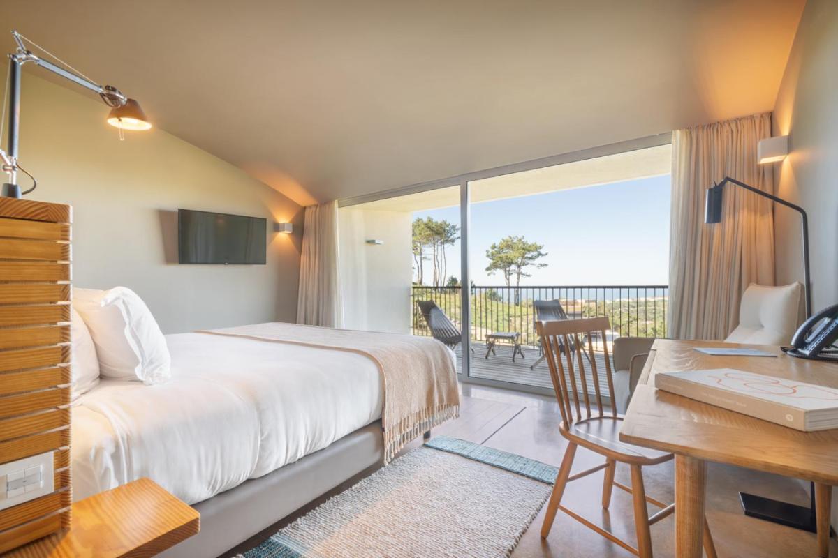 um quarto de hotel com uma cama, uma secretária e uma vista em Immerso Hotel, a Member of Design Hotels na Ericeira