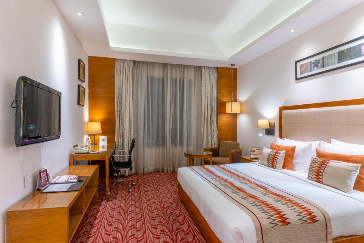 a hotel room with a large bed and a desk at Pride Plaza Hotel, Kolkata in Kolkata