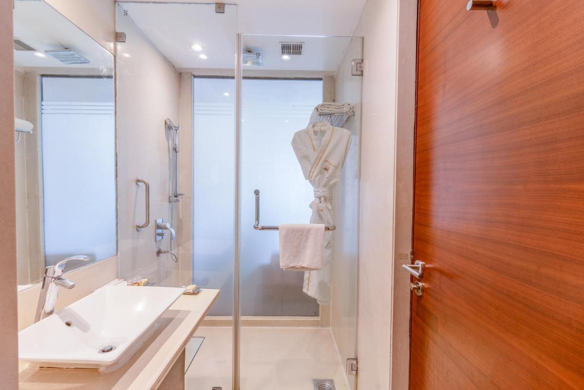 a bathroom with a sink and a glass shower door at Pride Plaza Hotel, Kolkata in Kolkata