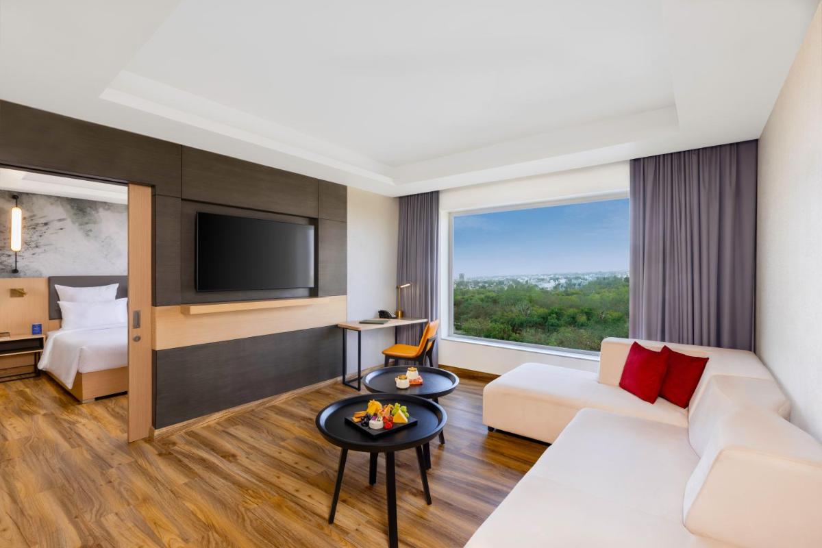 a hotel room with a couch and a tv at Novotel Jaipur Convention Centre in Jaipur