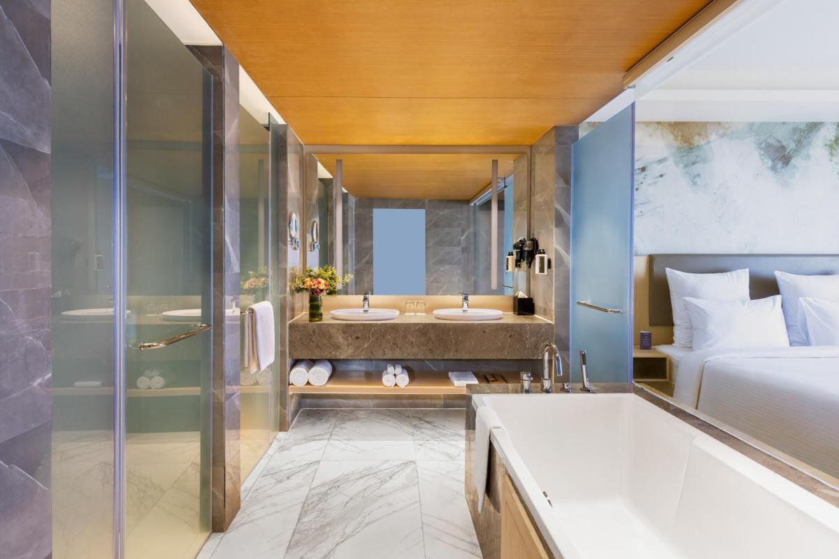 a bathroom with two sinks and a bed and a tub at Novotel Jaipur Convention Centre in Jaipur