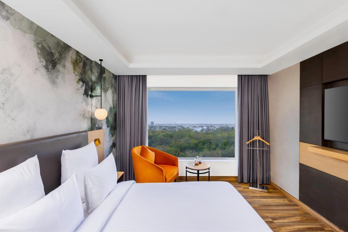 a hotel room with a bed and a window at Novotel Jaipur Convention Centre in Jaipur