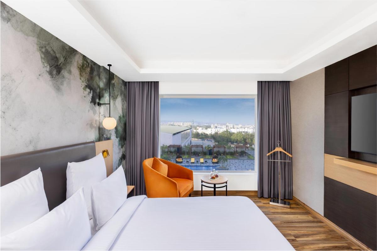 a hotel room with a bed and a window at Novotel Jaipur Convention Centre in Jaipur