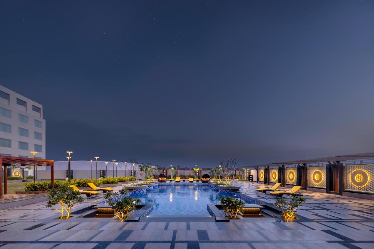a large swimming pool with chairs and a building at Novotel Jaipur Convention Centre in Jaipur