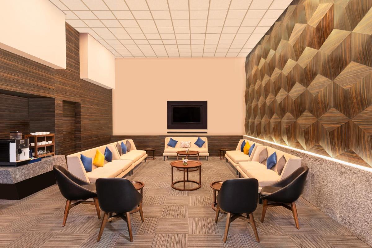 a waiting room with couches and a tv at Novotel Jaipur Convention Centre in Jaipur