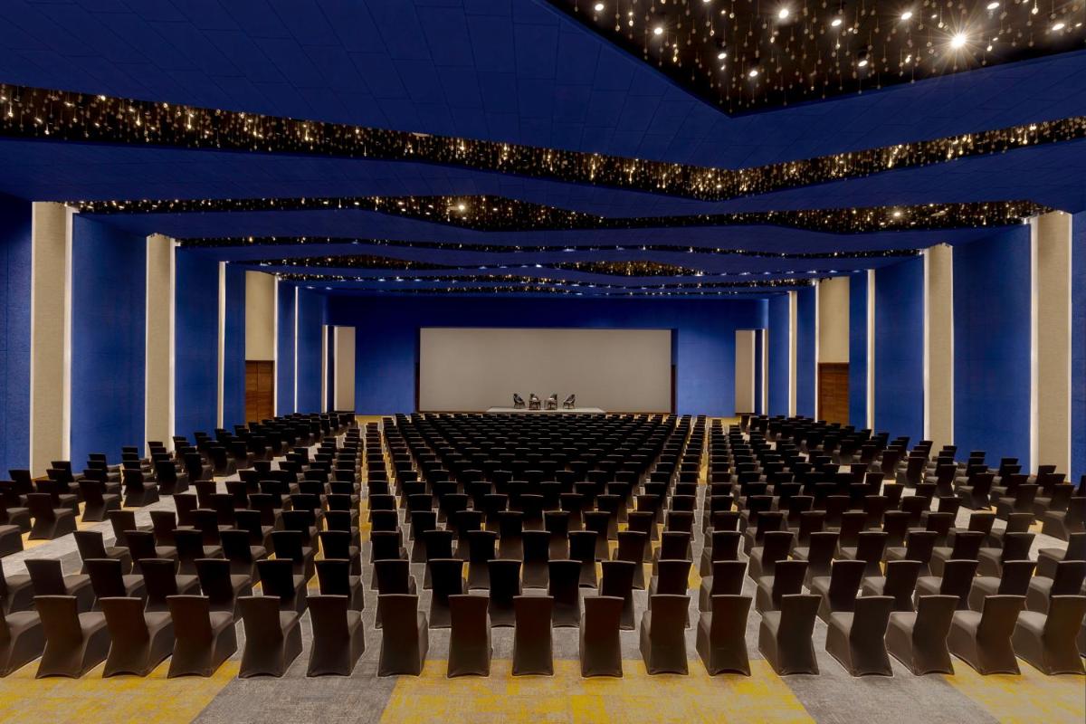 a large room with a stage with chairs and a screen at Novotel Jaipur Convention Centre in Jaipur