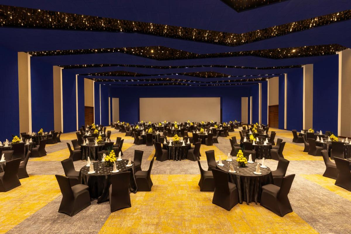 a large banquet hall with black tables and chairs at Novotel Jaipur Convention Centre in Jaipur