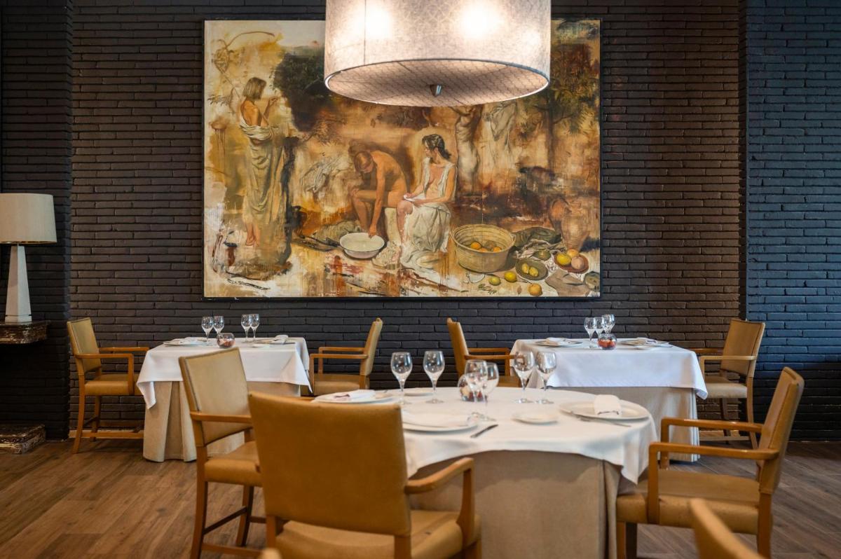 Un restaurante con mesas y sillas blancas y un cuadro. en Hesperia Barcelona Sant Just, en Sant Just Desvern