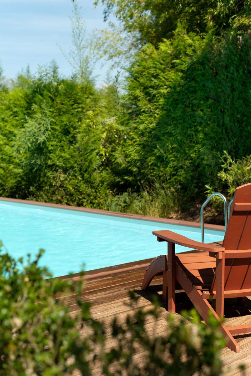 Un banco de madera sentado junto a una piscina. en A Quinta Da Auga Hotel Spa Relais & Chateaux, en Santiago de Compostela