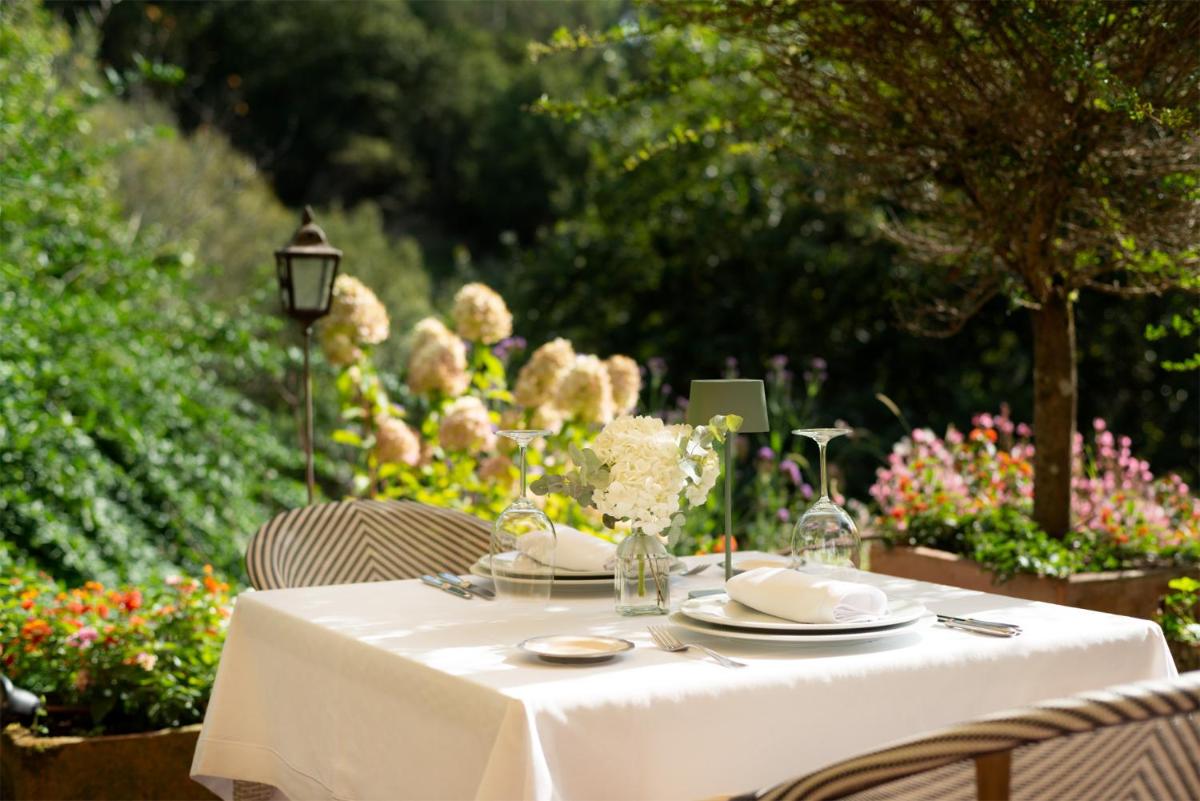 Una mesa con un mantel blanco y platos encima. en A Quinta Da Auga Hotel Spa Relais & Chateaux, en Santiago de Compostela