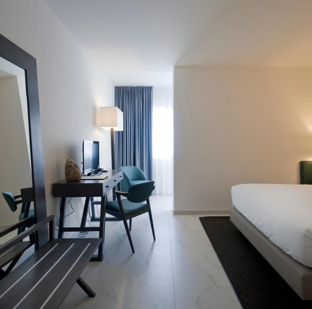 um quarto de hotel com uma cama e uma escrivaninha com um computador em Furadouro Boutique Hotel Beach & SPA em Ovar