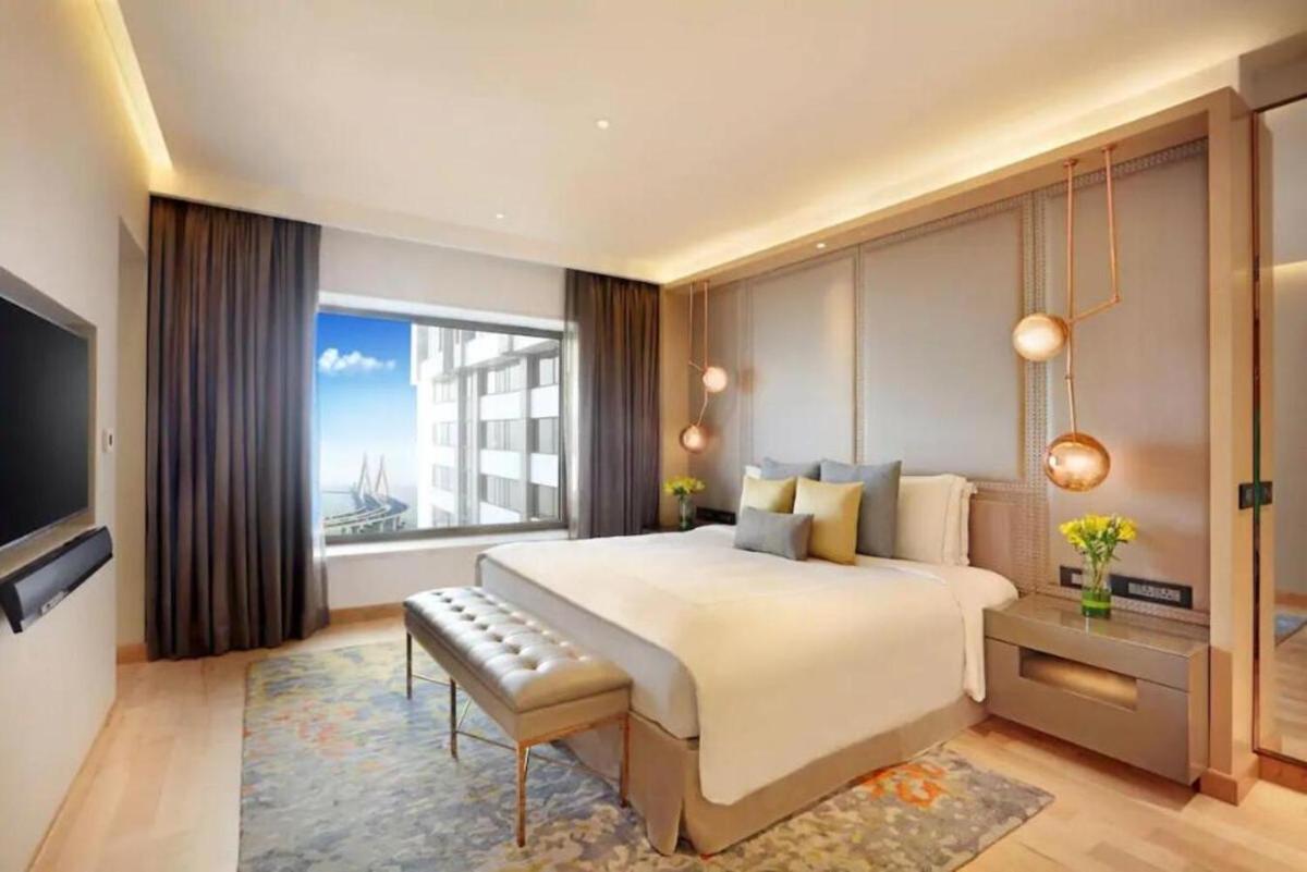 a bedroom with a large bed and a large window at Taj Lands End in Mumbai a bedroom with a large bed and a large window at Taj Lands End in Mumbai