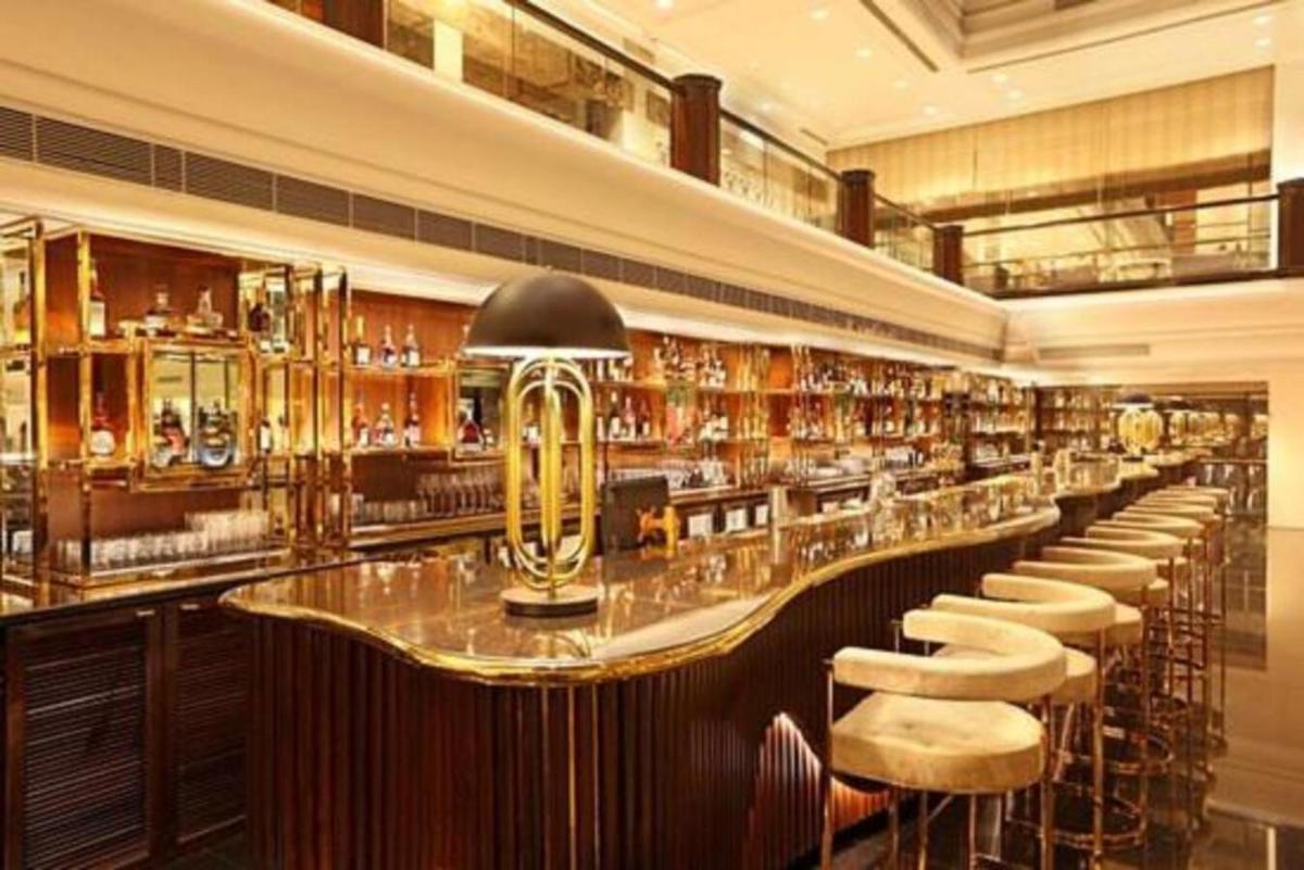 a bar with a long counter and stools in a room at Taj Lands End in Mumbai a bar with a long counter and stools in a room at Taj Lands End in Mumbai