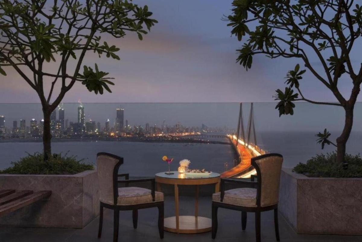 a table and chairs with a view of the city at Taj Lands End in Mumbai a table and chairs with a view of the city at Taj Lands End in Mumbai