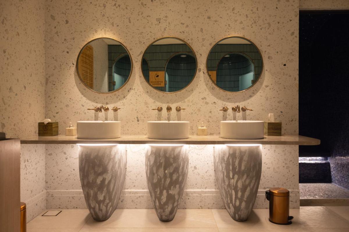 a bathroom with three sinks and three mirrors at Taj Lands End in Mumbai a bathroom with three sinks and three mirrors at Taj Lands End in Mumbai