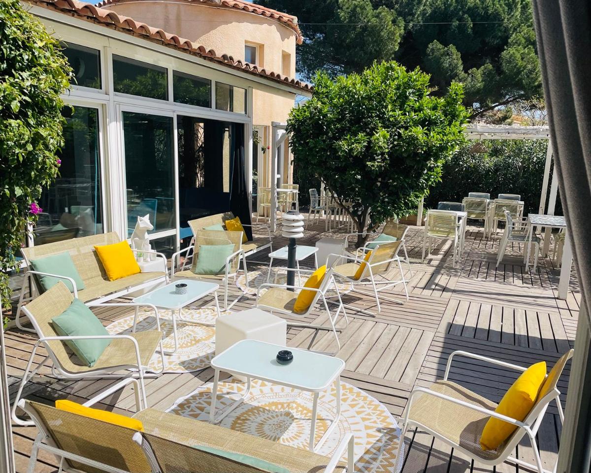 un groupe de chaises et de tables sur une terrasse dans l'établissement Hotel & Spa Gil de France Cap d'Agde, au Cap d'Agde