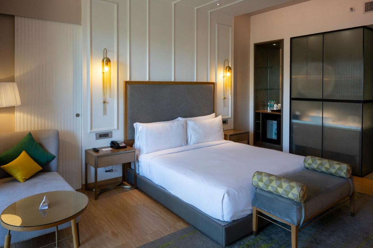 a hotel room with a large bed and a couch at Holiday Inn Goa Candolim in Candolim a hotel room with a large bed and a couch at Holiday Inn Goa Candolim in Candolim