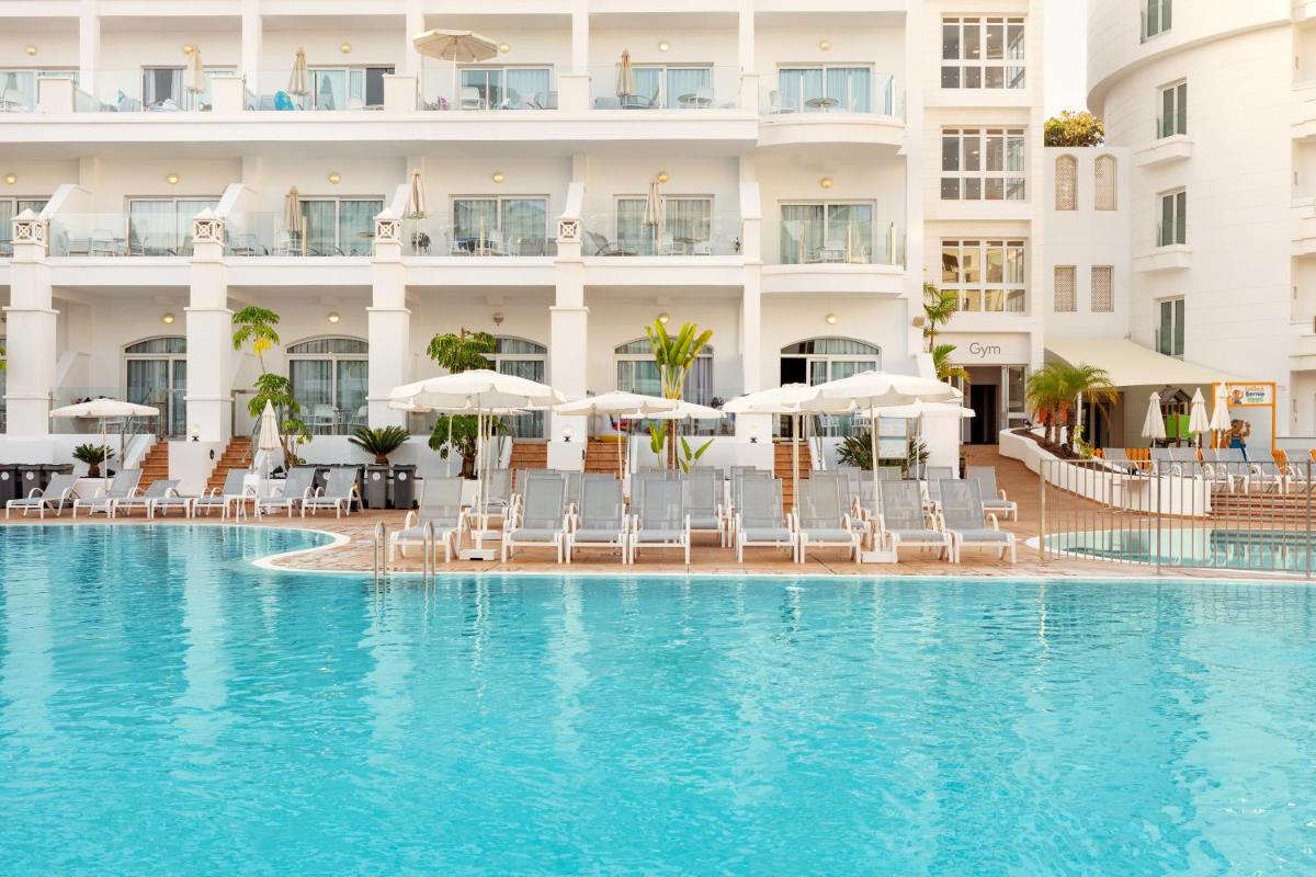 Una piscina de hotel con sillas y sombrillas. en Sunwing Fañabe Beach, en Adeje