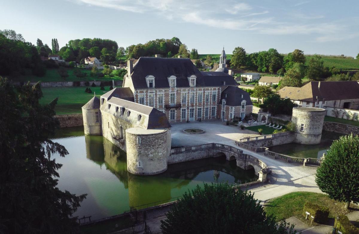 - une vue aérienne sur un grand bâtiment avec une rivière dans l'établissement Le Château d'Etoges - Champagne, à Étoges
