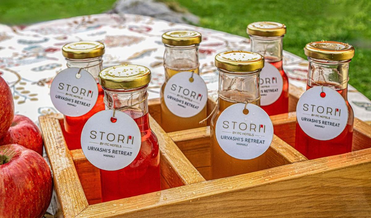 a wooden crate with four bottles of syrup and apples at Storii By ITC Hotels Urvashis Retreat, Manali in Manāli a wooden crate with four bottles of syrup and apples at Storii By ITC Hotels Urvashis Retreat, Manali in Manāli