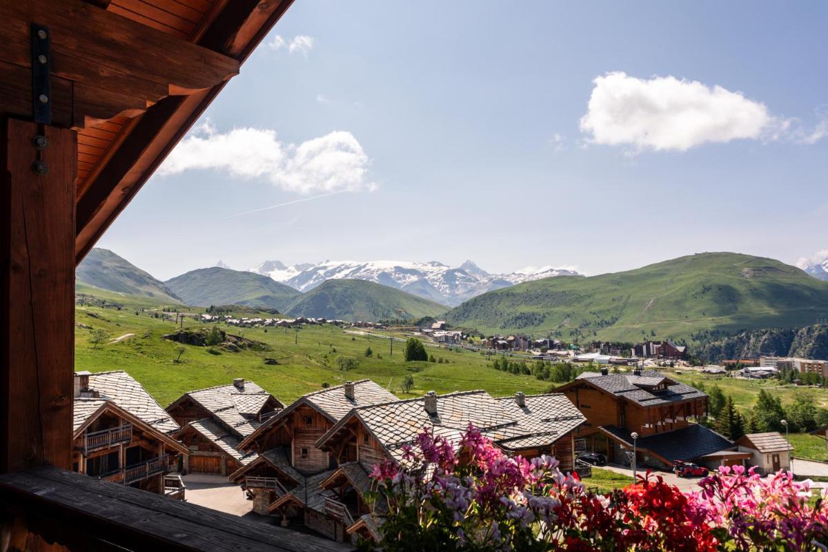 une vue d'un village avec des montagnes en arrière-plan dans l'établissement Hôtel Au Chamois d'Or by Les Etincelles, à L'Alpe-d'Huez