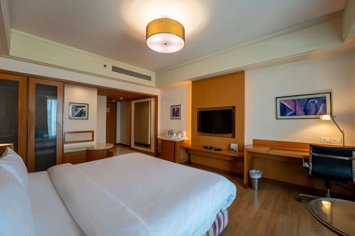 a bedroom with a bed and a desk and a television at Radisson Blu Hotel, Indore in Indore