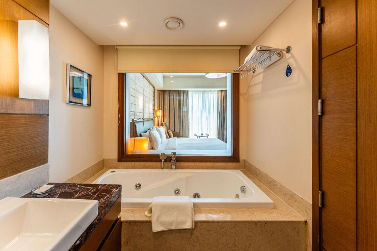 a bathroom with a large tub and a large mirror at Radisson Blu Hotel, Indore in Indore